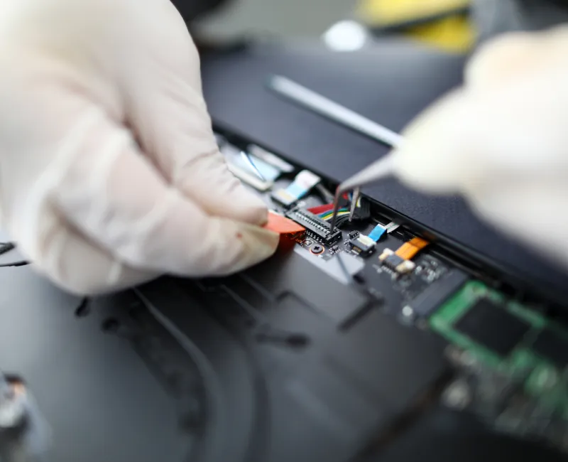 Técnico com luvas fazendo manutenção em um painel eletrônico